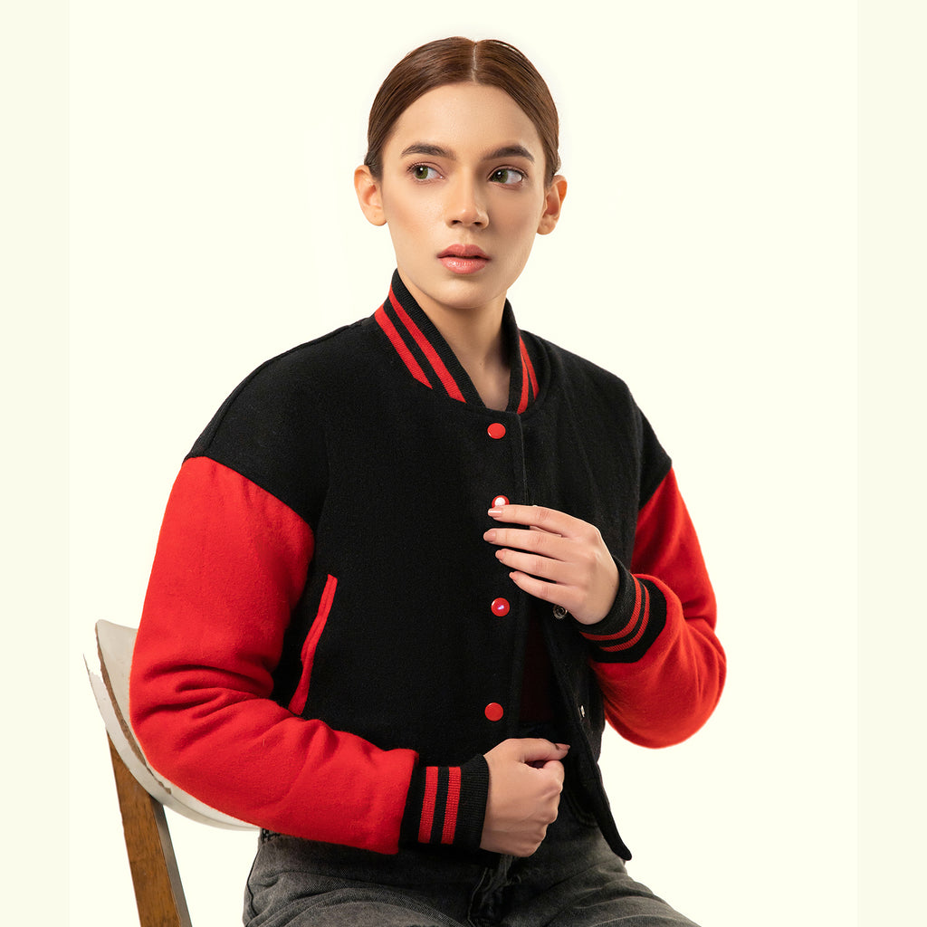 Person wearing a black and red varsity crop jacket on a white background