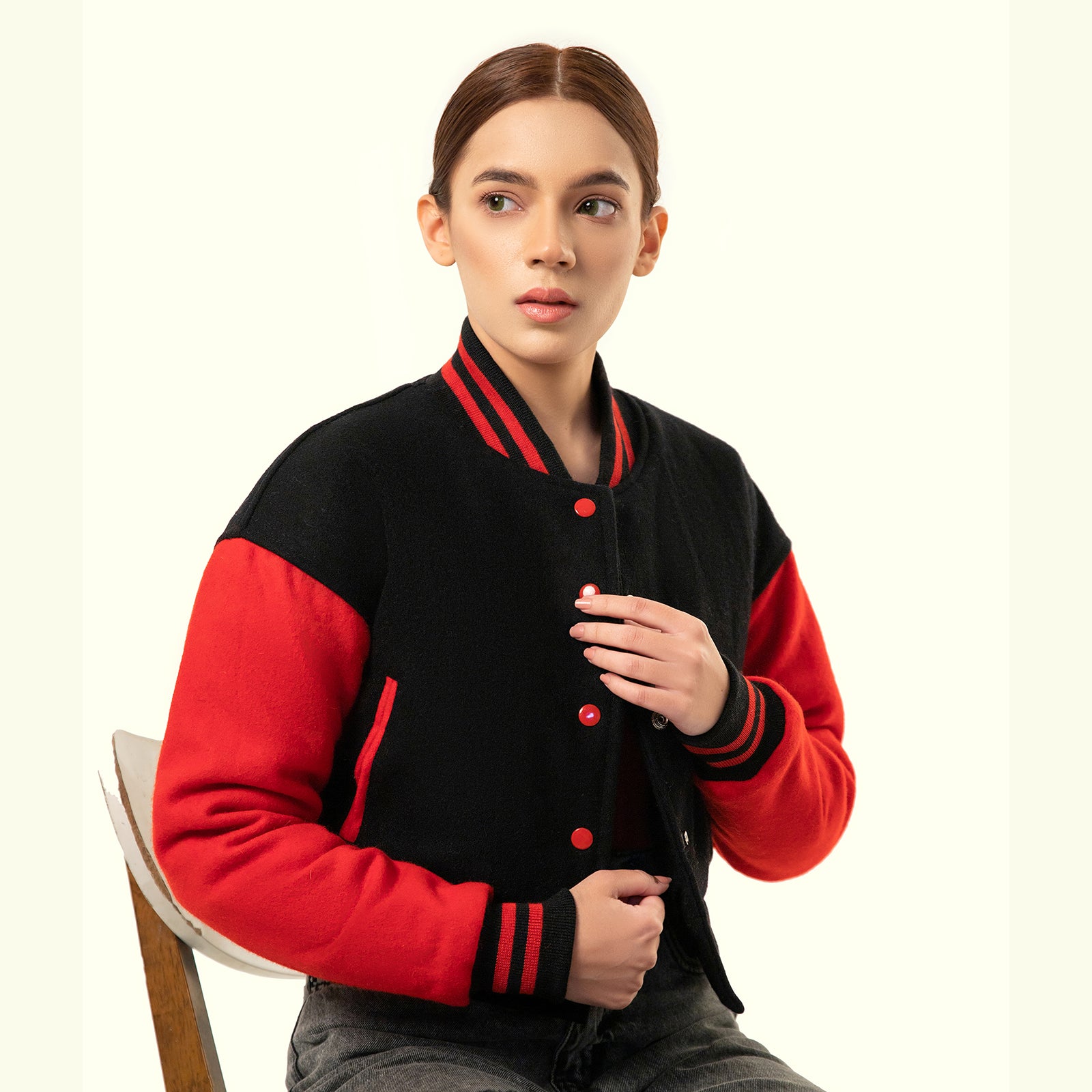 Person wearing a black and red varsity crop jacket on a white background