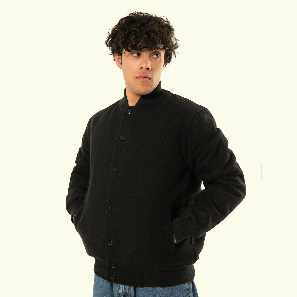 Person wearing a black varsity jacket on a white background