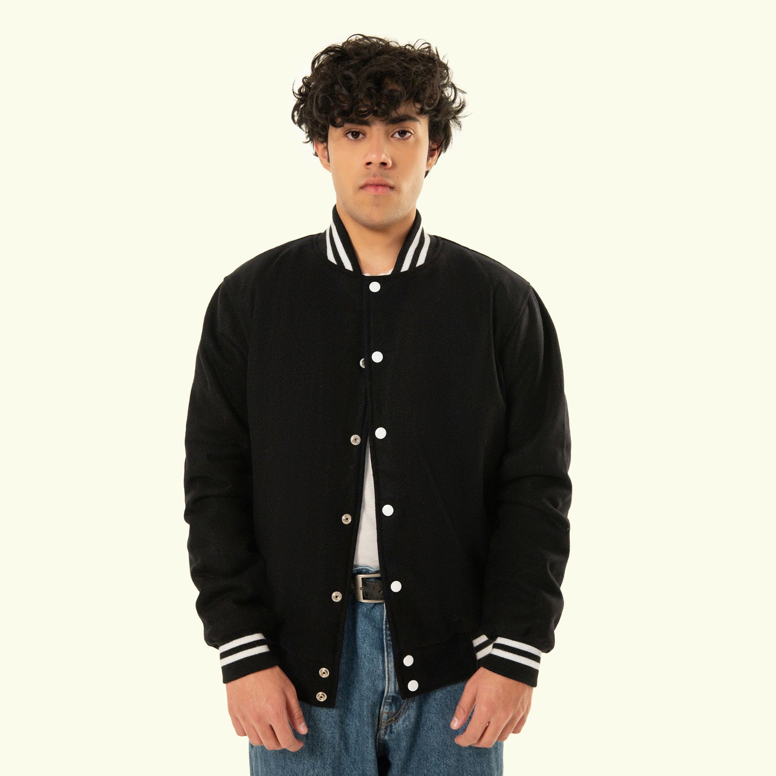 Person wearing a Navy blue varsity jacket with white accents on a plain background