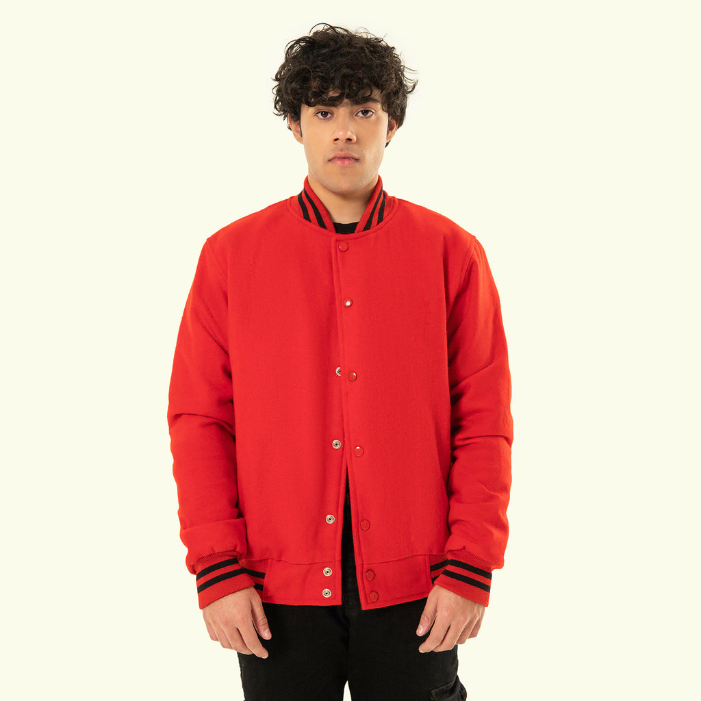 Person wearing a red varsity jacket with black trim on a white background