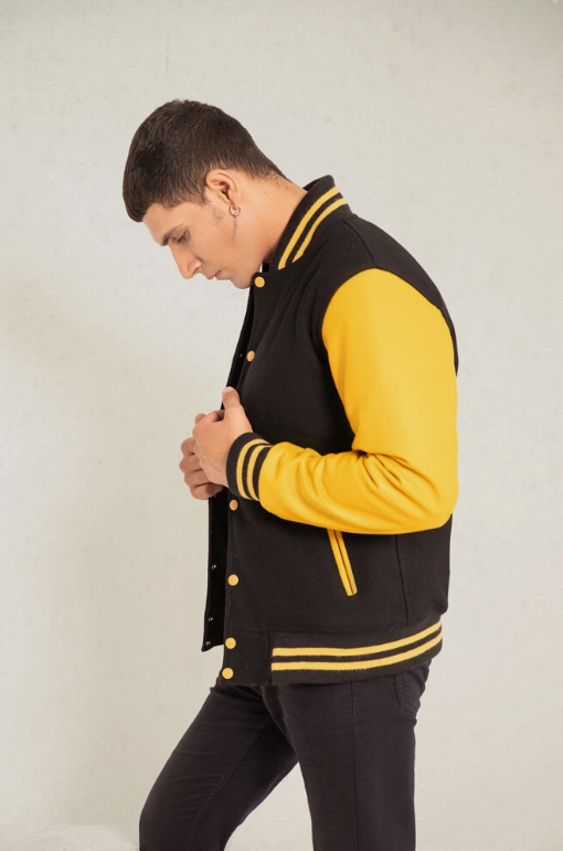 Person wearing a black and yellow varsity jacket on a plain background