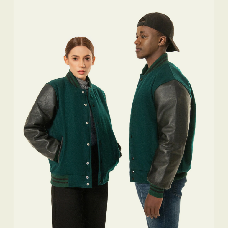 Two people wearing green letterman jackets with black sleeves on a plain background